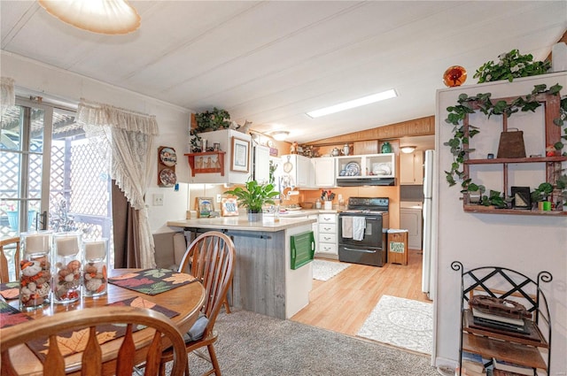 kitchen featuring kitchen peninsula, vaulted ceiling, white cabinets, black appliances, and light wood-type flooring