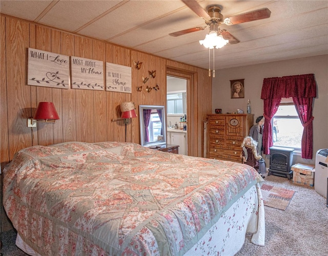 carpeted bedroom with ceiling fan and wood walls