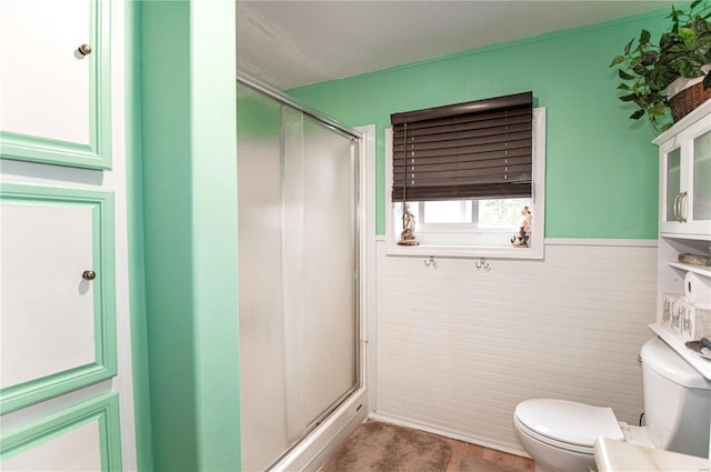 bathroom featuring a shower with shower door and toilet