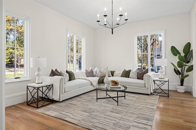 living room featuring an inviting chandelier, light hardwood / wood-style flooring, and a healthy amount of sunlight