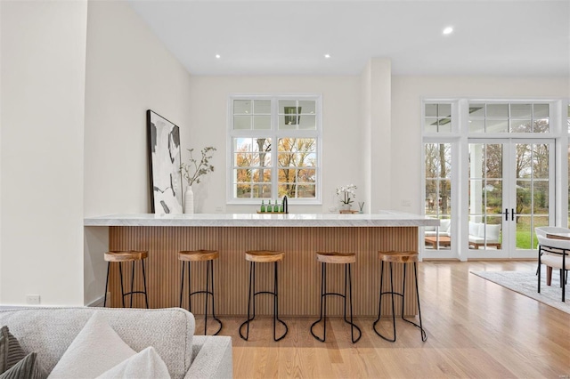 kitchen with a breakfast bar area, french doors, and light wood-type flooring