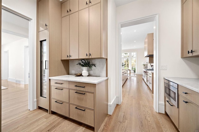 kitchen with stainless steel appliances, light brown cabinets, and light hardwood / wood-style floors