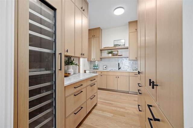 kitchen featuring tasteful backsplash, sink, light hardwood / wood-style floors, light stone countertops, and light brown cabinets