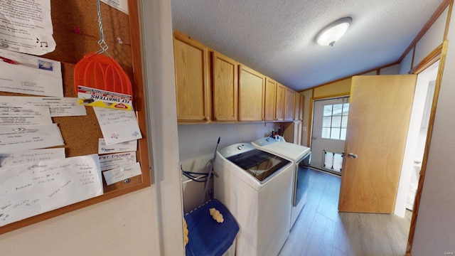 clothes washing area featuring cabinets, a textured ceiling, washing machine and dryer, and light hardwood / wood-style floors