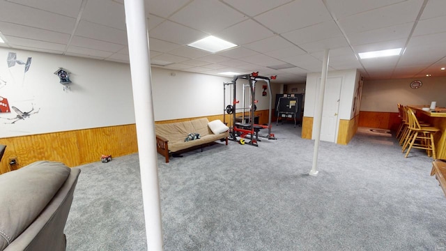 playroom with carpet floors, a paneled ceiling, and wood walls