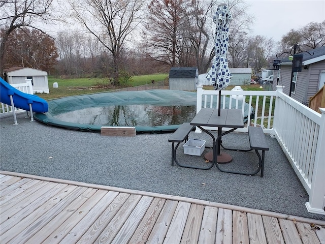 wooden deck featuring a covered pool and a storage unit