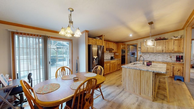 dining space with sink, light hardwood / wood-style flooring, a notable chandelier, crown molding, and lofted ceiling