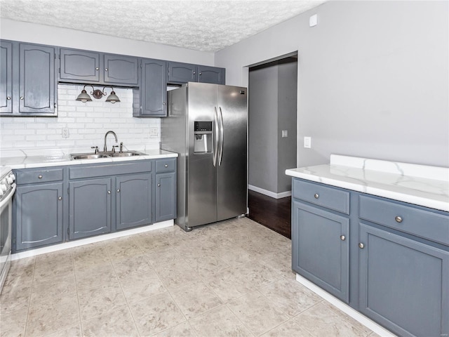 kitchen with backsplash, sink, stainless steel appliances, and a textured ceiling