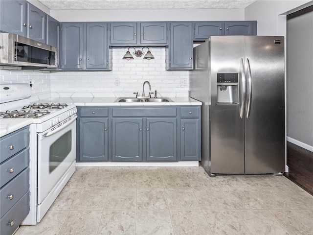 kitchen featuring blue cabinetry, decorative backsplash, sink, and stainless steel appliances