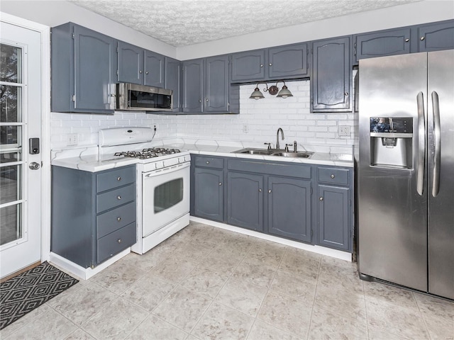 kitchen with decorative backsplash, sink, a textured ceiling, and appliances with stainless steel finishes