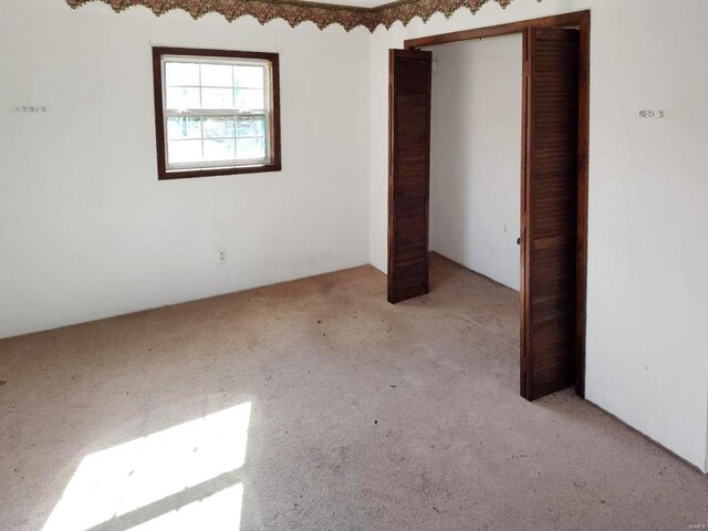 unfurnished bedroom featuring light carpet and a closet