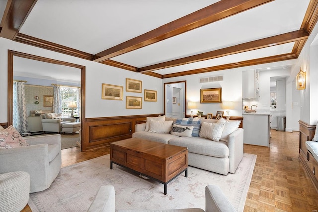 living room featuring beam ceiling, light parquet flooring, and crown molding