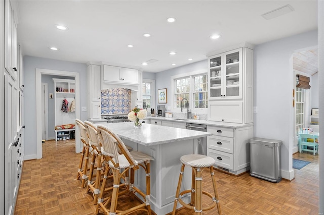 kitchen featuring light parquet flooring, white cabinetry, a kitchen island, and sink