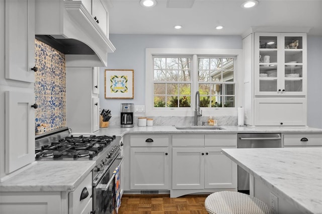 kitchen with dark parquet flooring, white cabinets, sink, light stone countertops, and appliances with stainless steel finishes