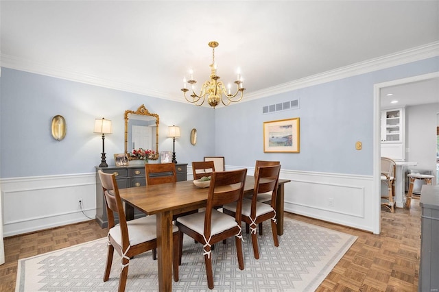 dining area with parquet floors, a chandelier, and ornamental molding