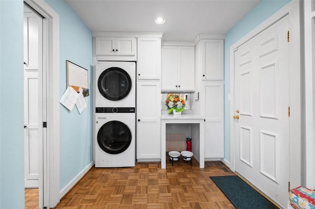 clothes washing area with cabinets, dark parquet flooring, and stacked washer and clothes dryer