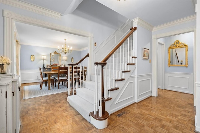 stairway with parquet flooring, crown molding, and a chandelier