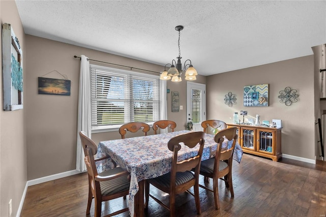 dining area featuring a textured ceiling, dark wood-type flooring, and an inviting chandelier