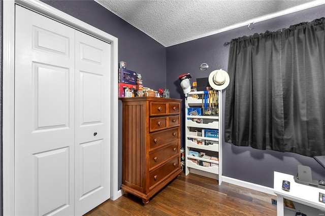 bedroom with a textured ceiling, a closet, and dark wood-type flooring