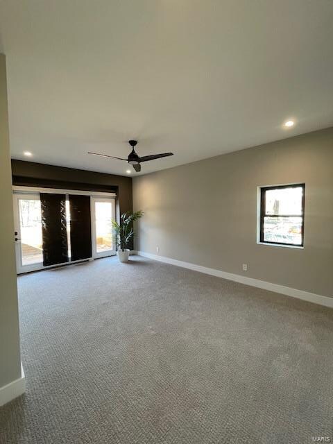 empty room with carpet flooring, ceiling fan, and a healthy amount of sunlight