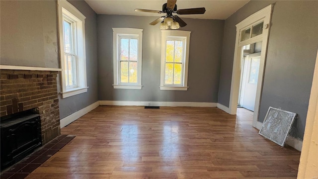 interior space featuring a wood stove, ceiling fan, and dark wood-type flooring