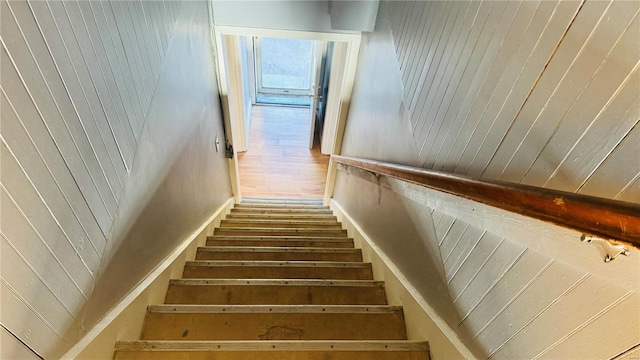 stairway with wooden walls and wood-type flooring