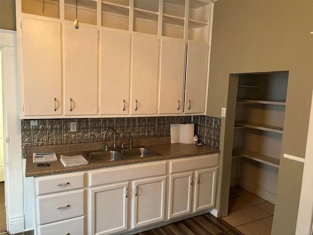 kitchen featuring dark tile patterned flooring, white cabinetry, sink, and tasteful backsplash