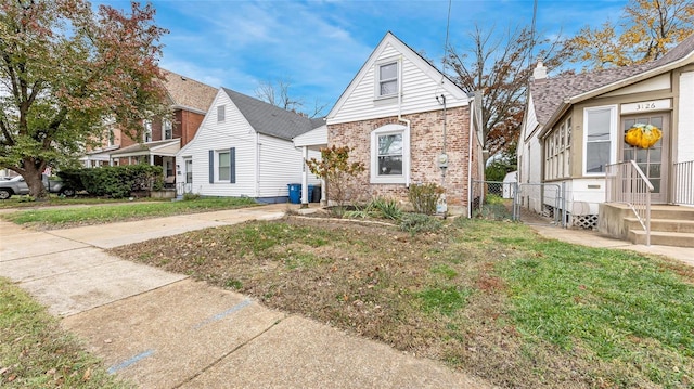 view of front facade featuring brick siding, a front yard, and fence