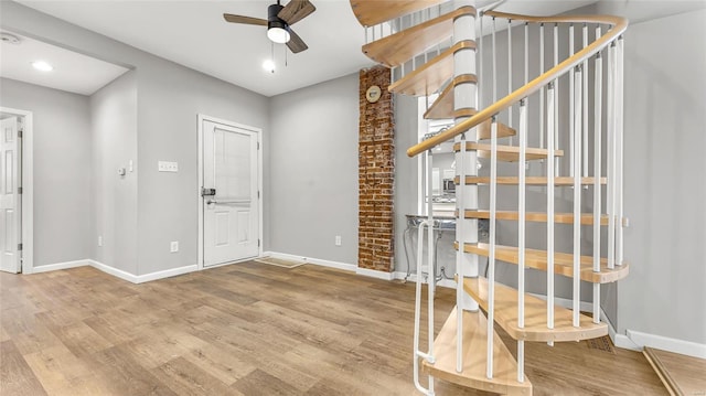 foyer featuring stairway, baseboards, a ceiling fan, and wood finished floors