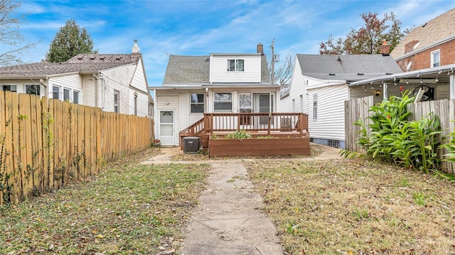 back of property featuring a fenced backyard, a yard, a deck, and roof with shingles