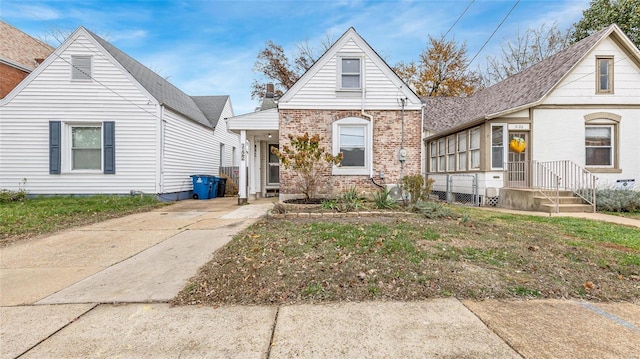 view of front of house with a sunroom, brick siding, and a front lawn