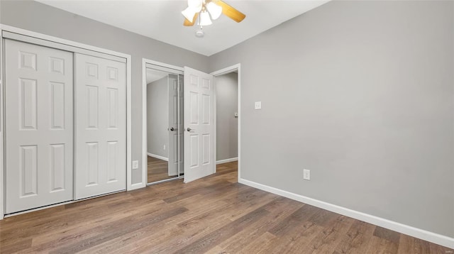 unfurnished bedroom featuring multiple closets, ceiling fan, baseboards, and wood finished floors