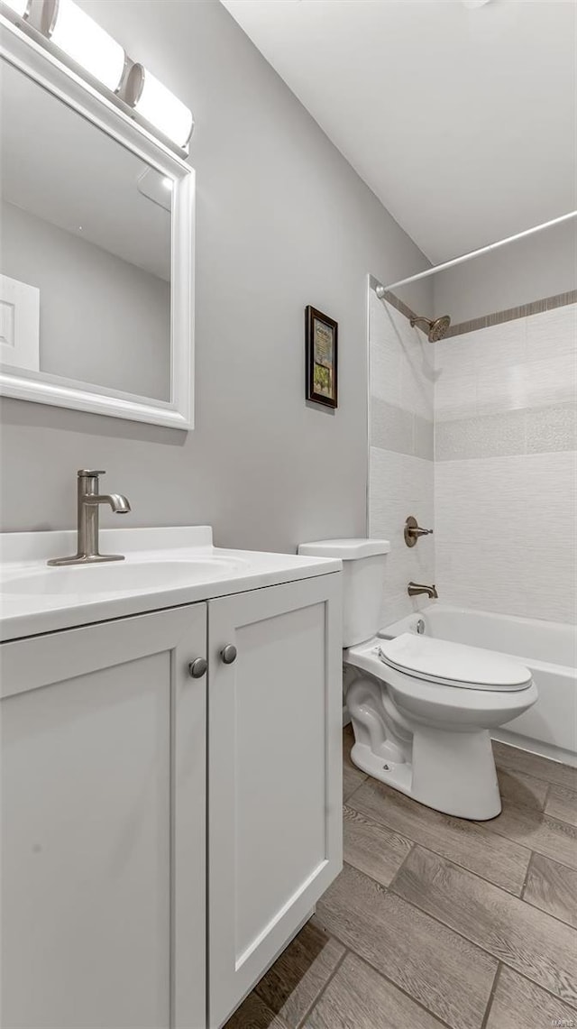 bathroom with toilet,  shower combination, wood finished floors, and vanity