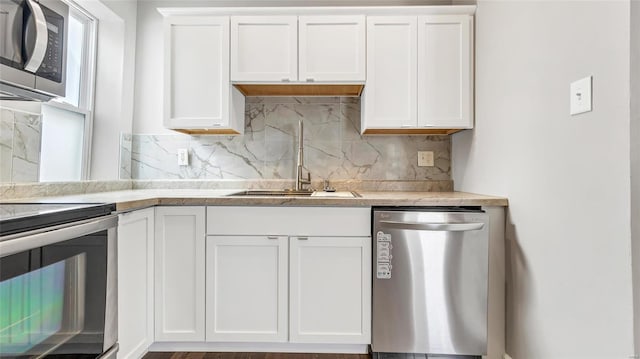 kitchen featuring appliances with stainless steel finishes, white cabinets, and a sink