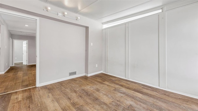 spare room with visible vents, baseboards, and wood finished floors