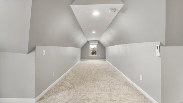 additional living space with lofted ceiling, light colored carpet, and baseboards