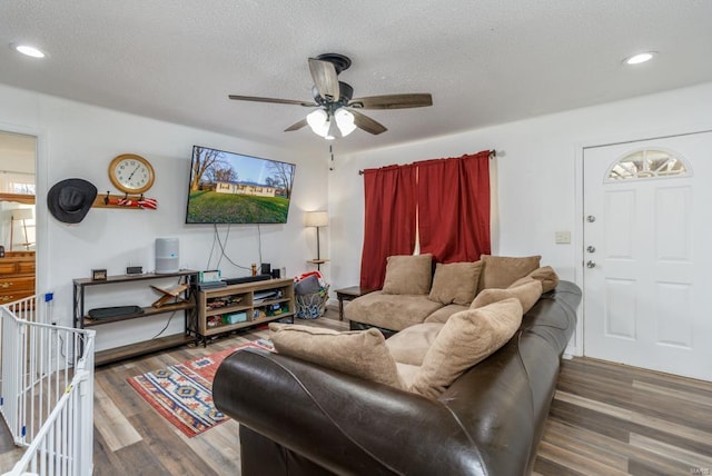 living room featuring ceiling fan, dark wood-type flooring, and a textured ceiling