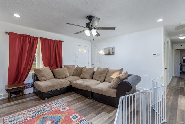 living room featuring hardwood / wood-style flooring, ceiling fan, and a textured ceiling