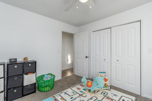 recreation room with ceiling fan, carpet floors, and a textured ceiling