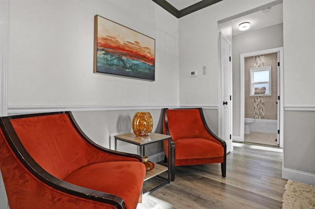 sitting room with wood-type flooring and ornamental molding