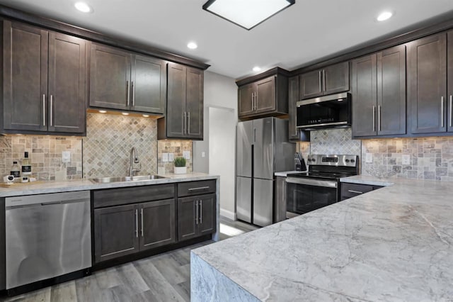 kitchen featuring sink, stainless steel appliances, tasteful backsplash, light hardwood / wood-style flooring, and dark brown cabinets