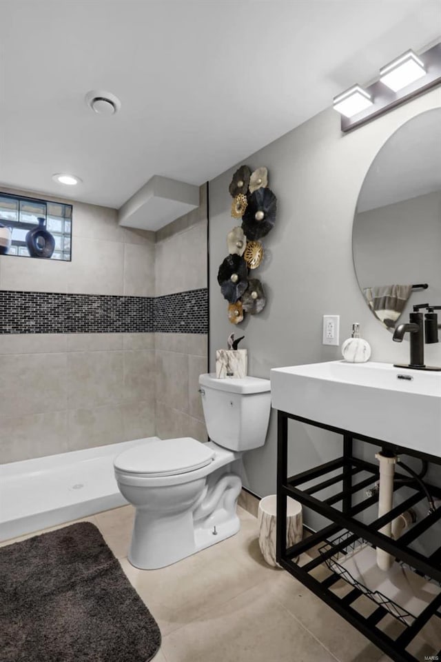 bathroom featuring tile patterned floors, a tile shower, and toilet