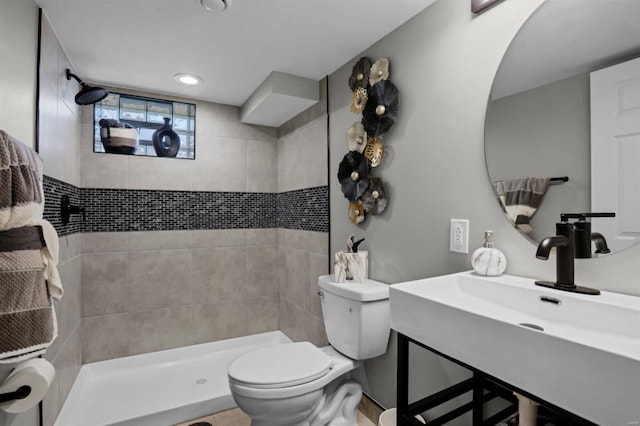 bathroom featuring tiled shower, toilet, and sink