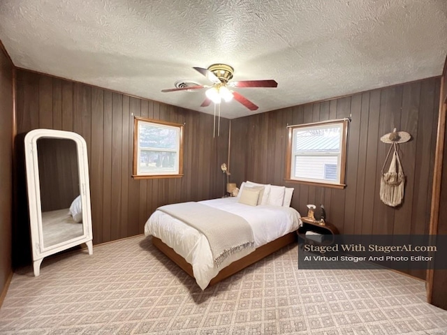 bedroom featuring ceiling fan, wood walls, a textured ceiling, and light carpet