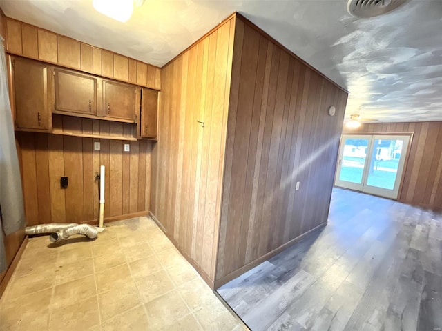 clothes washing area featuring cabinets and wood walls