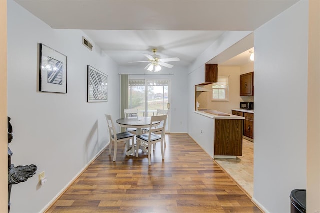 dining area with light wood-type flooring and ceiling fan