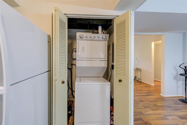 laundry room featuring stacked washing maching and dryer and light hardwood / wood-style floors