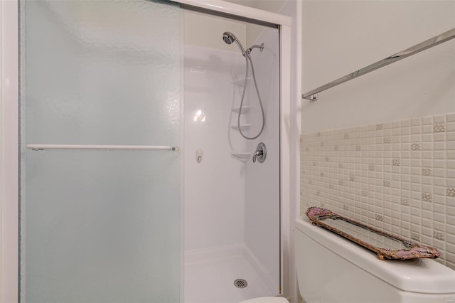 bathroom with toilet, an enclosed shower, and backsplash