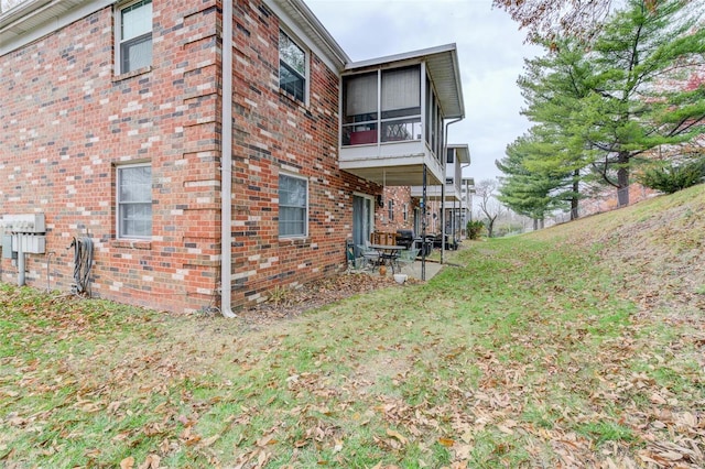 view of side of home featuring a sunroom and a lawn