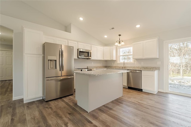 kitchen featuring white cabinets, appliances with stainless steel finishes, vaulted ceiling, and pendant lighting